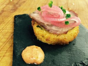 Fried Polenta Rounds Topped with Porchetta and Pickled Red Onions